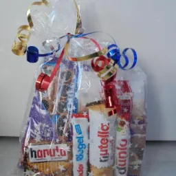 Przezroczysty worek foliowy, przewiązany wstążkami w kolorach złotym, srebrnym, czerwonym i niebieskim, wypełniony słodyczami: batoniki Kinder Riegel, Duplo, Nutella B-ready oraz wafelki Hanuta.