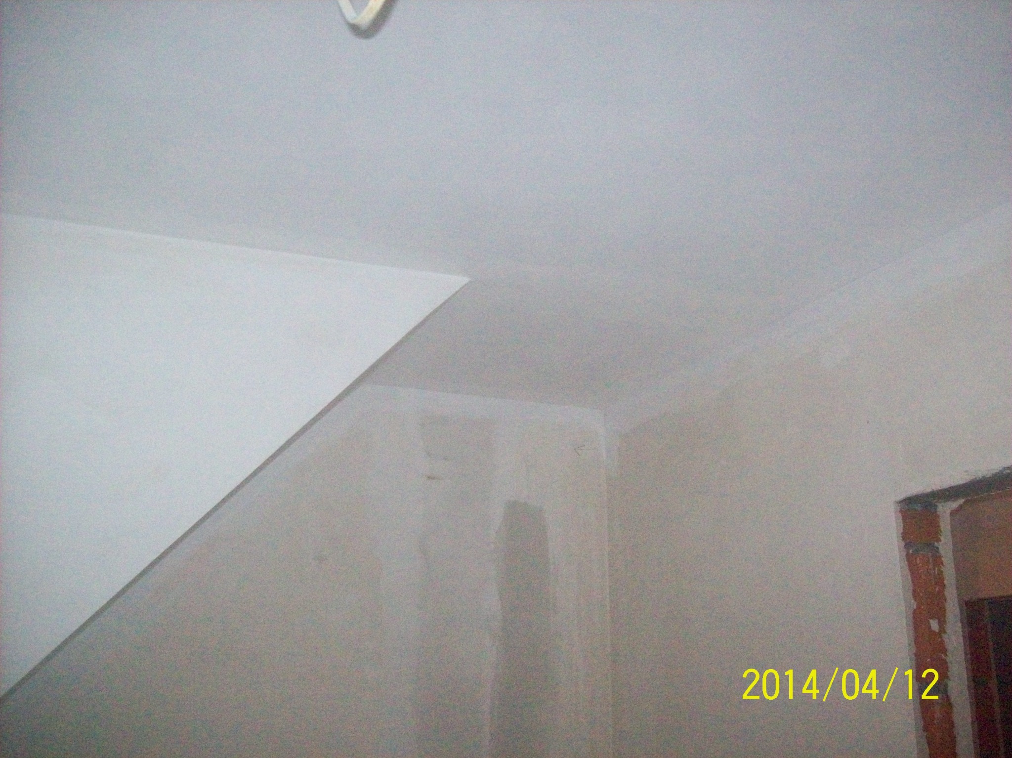 Ściana i sufit po nałożeniu gładzi szpachlowej, widoczne łączenia płyt kartonowo-gipsowych przed szlifowaniem, narożnik ściany z datą 2014/04/12 w prawym dolnym rogu.