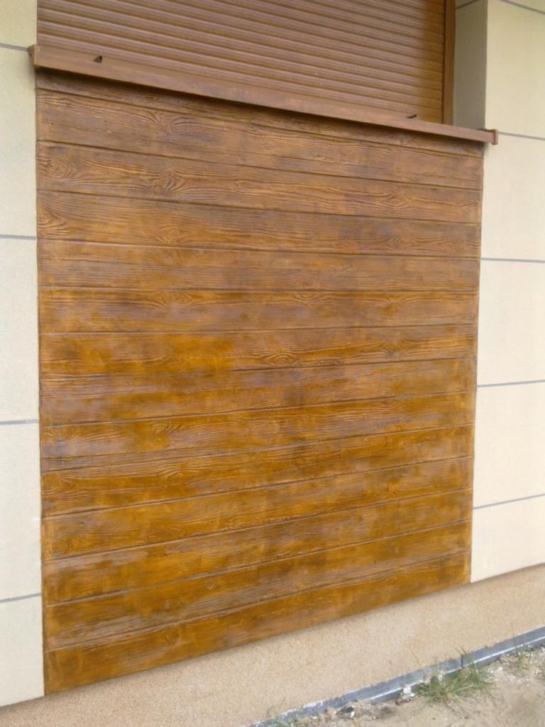 Elewacja budynku z ociepleniem imitującym drewniane deski, z widoczną roletą w górnej części.