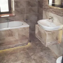 Wykończona łazienka z marmurowymi płytkami, podświetlaną wanną i umywalką na postumencie.