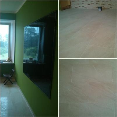 Wykończona podłoga z jasnych, prostokątnych płytek w pokoju z zielonymi ścianami i oknem. Widoczne detale ułożenia płytek i odbicie w szybie.