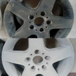 Porównanie: Obręcz samochodowa przed i po piaskowaniu oraz malowaniu proszkowym na jasny kolor. Górna część obręczy jest brudna i matowa, dolna po renowacji jest czysta i błyszcząca.