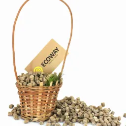 Wypełniony brązowymi kostkami wiklinowy koszyk z uchwytem, obok rozsypane kostki, widoczna etykieta z napisem 'ECOWAY harmony of nature' i źdźbła zielonej trawy.