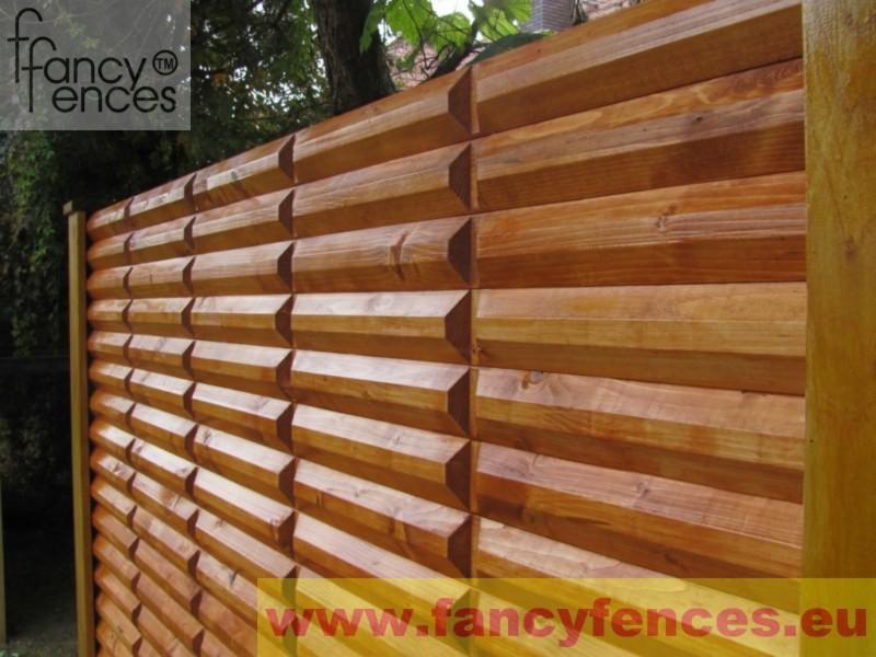 Drewniane ogrodzenie panelowe z poziomych desek o geometrycznym wzorze, zabezpieczone słupkiem z jasnego drewna.