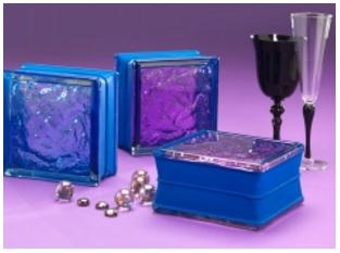 Dekoracyjne szklane pustaki w niebieskich i fioletowych odcieniach, ułożone na fioletowym tle obok szklanych ozdób i kieliszków.