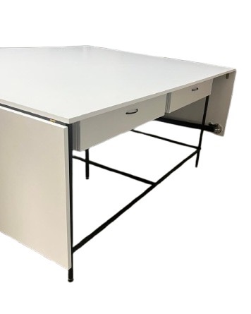 Biały stół z szufladami i czarną metalową podstawą, widoczny z boku pod kątem, na białym tle. Minimalistyczny design, proste uchwyty szuflad.