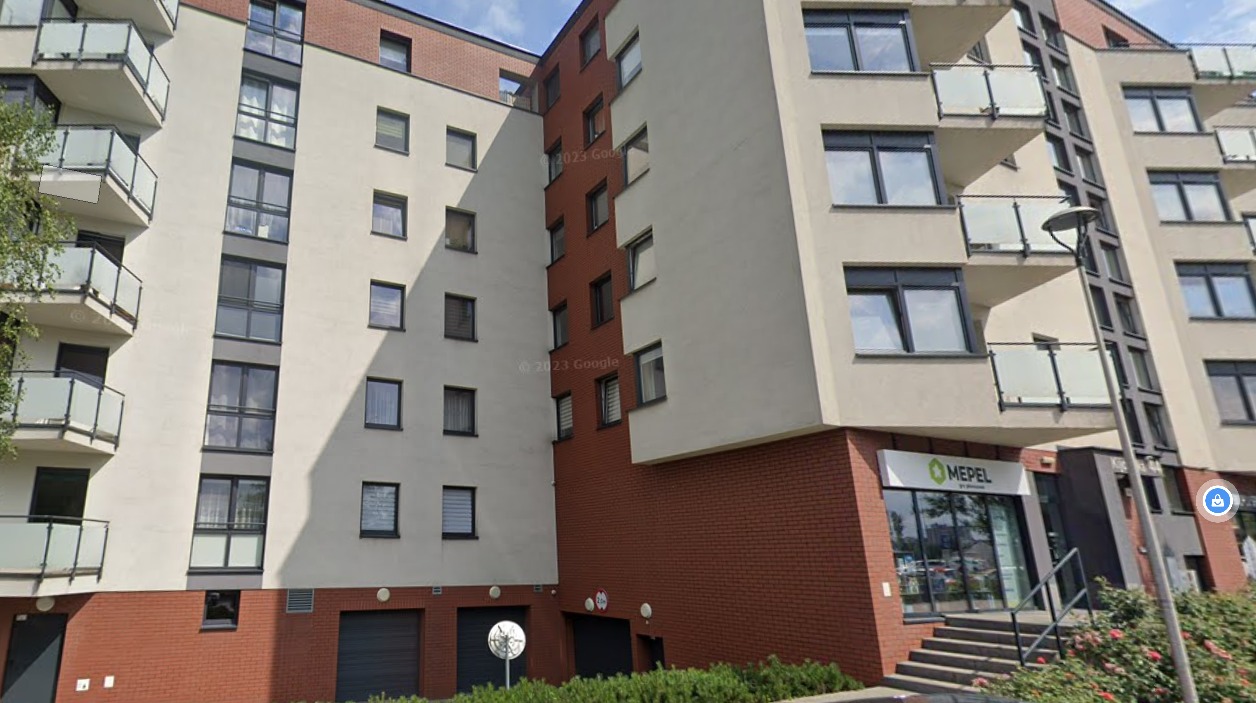 Nowoczesny budynek mieszkalny z balkonami i elementami z czerwonej cegły. Widoczny lokal usługowy na parterze z zielonym logo firmy 'MEPEL'.