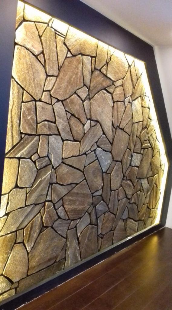 Ściana z kamienia dekoracyjnego z podświetleniem LED w Raba Wyżna, wykończona ciemną ramą.