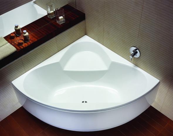 Biała, narożna wanna z półką i armaturą, uzupełniona drewnianą półką z akcesoriami w nowoczesnej łazience z beżowymi płytkami.