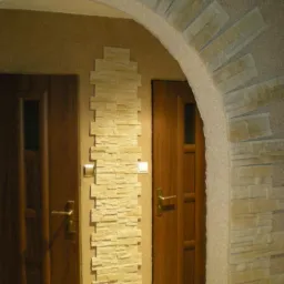 Aranżacja wnętrza z dwoma drewnianymi drzwiami, łukiem i pionowym panelem dekoracyjnym z kamienia elewacyjnego w odcieniach beżu i brązu.