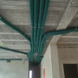 Zielone, karbowane rury wentylacyjne zamocowane do sufitu z betonu komórkowego w surowym wnętrzu budynku, widok z dołu.