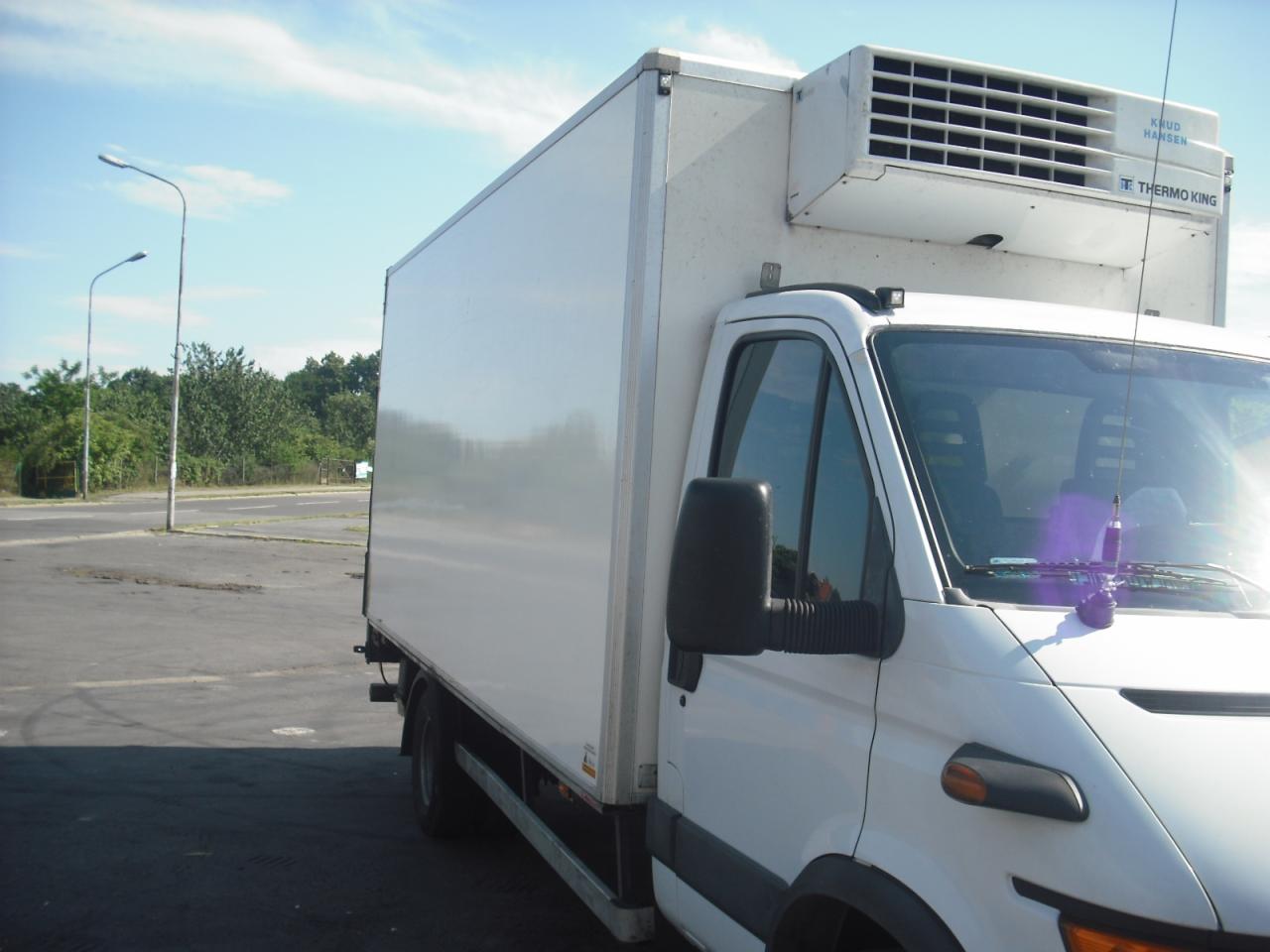 Biały samochód dostawczy z chłodnią Thermo King na parkingu, widok z boku na kabinę i część przestrzeni ładunkowej.