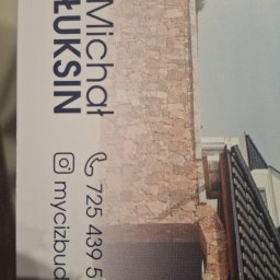 Michal88 - Kamienny mur z łukowym otworem, fragment budynku z dachem, wizytówka firmy budowlanej z logo, numerem telefonu i adresem strony internetowej.