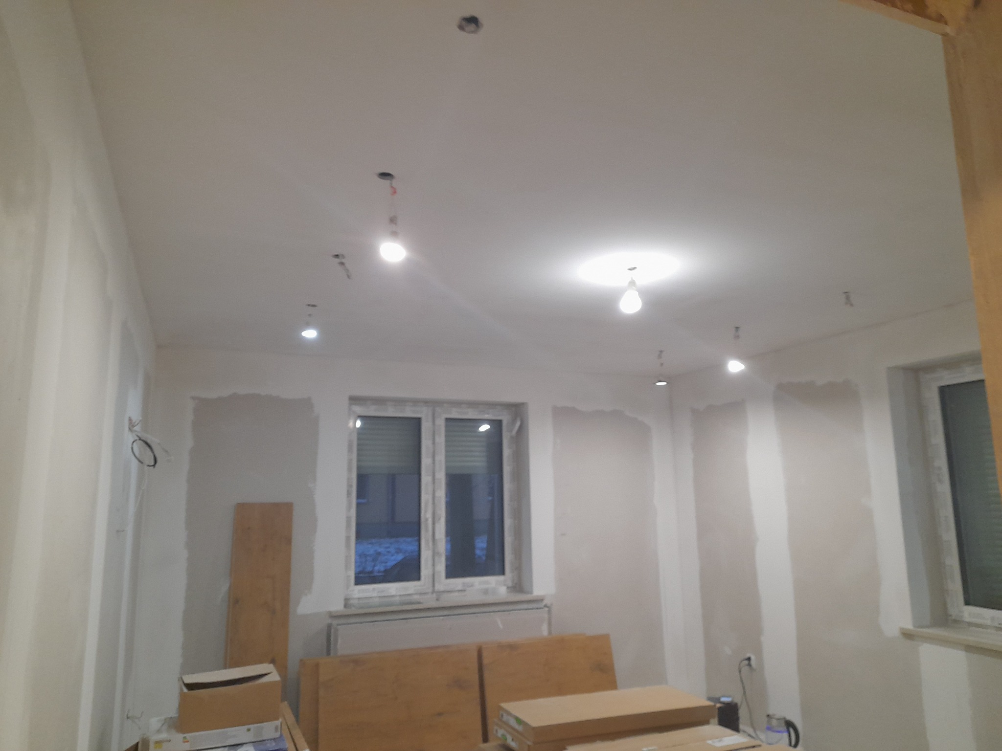 Pokój w trakcie szpachlowania ścian i sufitu, widoczne przygotowane płyty gipsowe i instalacja oświetleniowa.