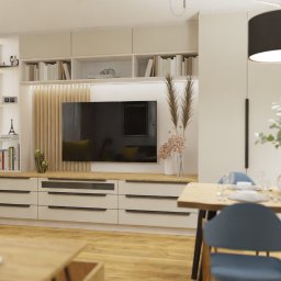 Aleksandra Bojakowska-Wszołek ALPRA - projektowanie wnętrz - Nowoczesny salon z drewnianymi akcentami: zabudowa TV z szufladami, półki z książkami, dekoracje roślinne i stół jadalny z niebieskimi krzesłami.