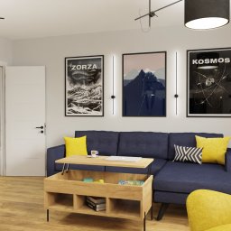 Aleksandra Bojakowska-Wszołek ALPRA - projektowanie wnętrz - Wnętrze salonu z granatową sofą, drewnianym stolikiem kawowym z podnoszonym blatem, żółtym fotelem, plakatami na ścianie i kotem na drapaku.