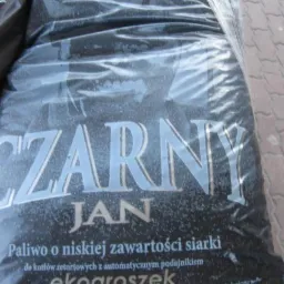 Worek z ekogroszkiem marki 'Czarny Jan' zapakowany w przezroczystą folię, widoczne hasło 'Paliwo o niskiej zawartości siarki'.