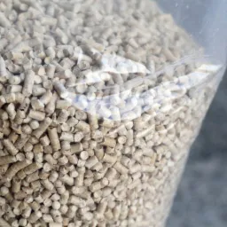 Wypełniony worek przezroczystego tworzywa z jasnymi, cylindrycznymi granulkami pelletu z widocznym logo producenta w lewym dolnym rogu.