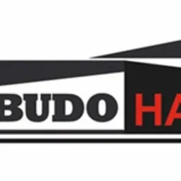 Logo firmy Budohal z napisem BUDO w kolorze czarnym i HAL w kolorze czerwonym, umieszczone na białym tle, z graficznym elementem przypominającym zarys hali w górnej części.