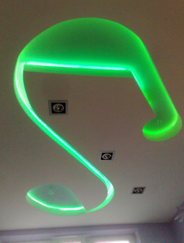 Nowoczesny sufit podwieszany z płyt gipsowo-kartonowych z zielonym oświetleniem LED, widoczne trzy kwadratowe lampy halogenowe wpuszczone w sufit.