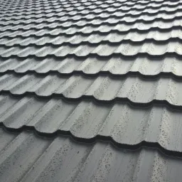 Szare dachówki modułowe z widocznymi kroplami deszczu, ułożone na dachu pod kątem, z bliska, z delikatnym połyskiem.