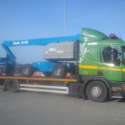 P.H.U. JANTRUCK s.c.Sebastian i Marcin Jankowiak - Laweta z podnośnikiem Genie S-45 na platformie. Zielona kabina Scania z napisem 'Pomoc Drogowa'. Błękitne niebo w tle. Widok z boku, światło dzienne.
