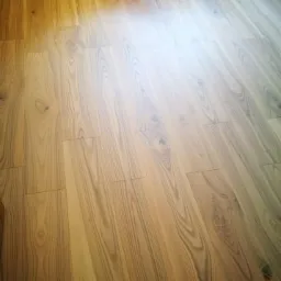 Ułożona, jasna podłoga z desek o wyraźnym rysunku drewna, widoczna z góry w ukośnym ujęciu.