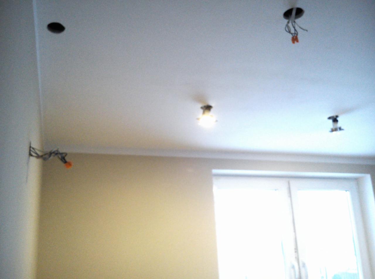 Poddasze w trakcie adaptacji: widoczne otwory w suficie, wystające przewody elektryczne i zamontowana listwa sufitowa przy ścianie.