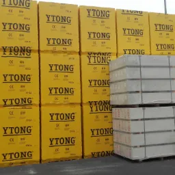 Magazyn z paletami żółtych paczek YTONG oraz paletami białych bloczków, całość zapakowana w folię.