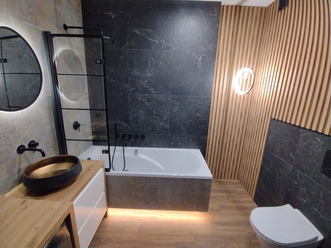 Nowoczesna łazienka z wanną, kabiną prysznicową i umywalką nablatową. Aranżacja łączy drewno i marmur, tworząc elegancki i funkcjonalny wystrój.