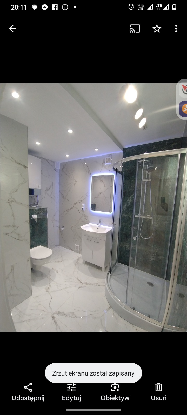 Elegancka łazienka po remoncie z marmurowymi płytkami, kabiną prysznicową i podświetlanym lustrem. Nowoczesne oświetlenie sufitowe.