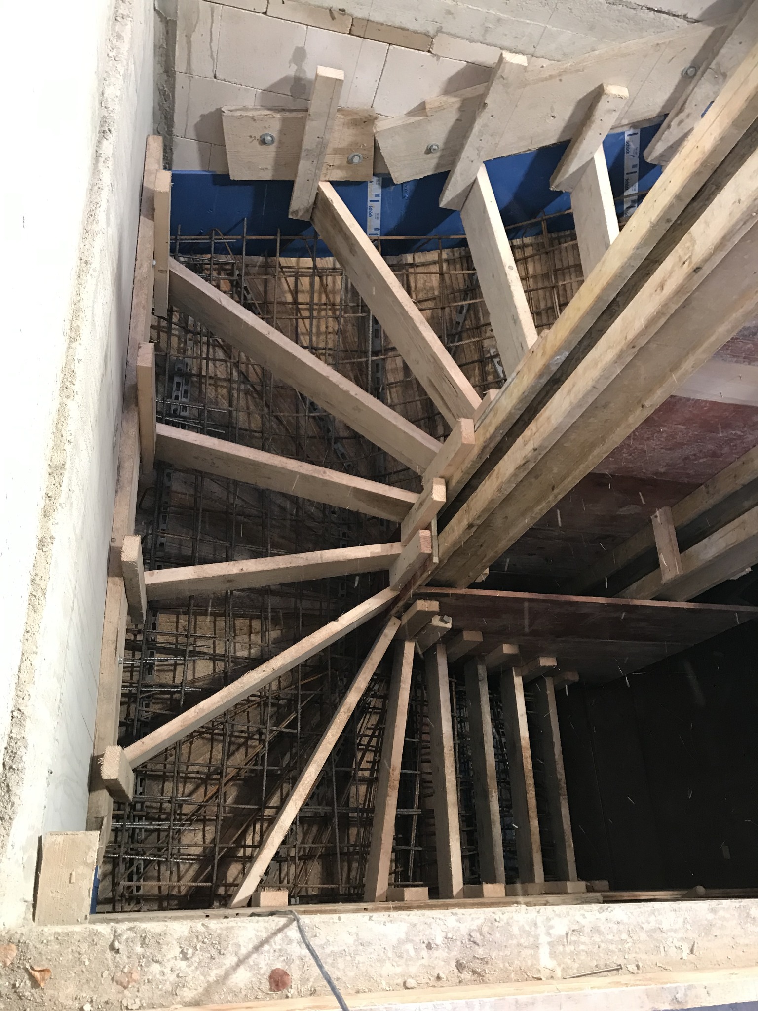 Zbrojenie schodów z drewnianym szalunkiem na placu budowy w Kościerzynie, widok z góry na konstrukcję ze stalowych prętów i drewnianych belek.