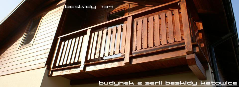Drewniany balkon domu z serii Beskidy 134 w Katowicach, z widoczną elewacją i oknem poddaszowym, w ciepłym oświetleniu.