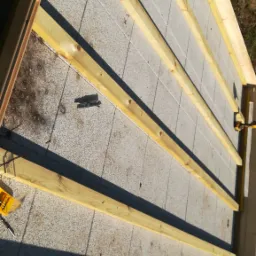 Konstrukcja drewniana poddasza z widocznymi belkami i narzędziami, przygotowana do dalszych prac izolacyjnych.