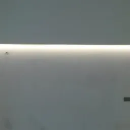 Wnękowe oświetlenie LED zamontowane wzdłuż ściany, z widocznymi puszkami instalacyjnymi i fragmentem drzwi po prawej stronie.