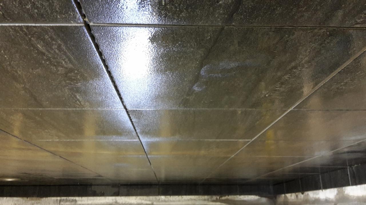 Błyszczące, świeżo położone szare płytki na podłodze w Nowym Tomyślu, z widocznymi fugami i odbiciami światła, sugerujące mokrą powierzchnię.