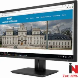 Monitor wyświetla stronę internetową z budynkiem w Chróstniku. Widok z boku, ukazujący detale strony i jakość obrazu. Logo firmy w prawym dolnym rogu.