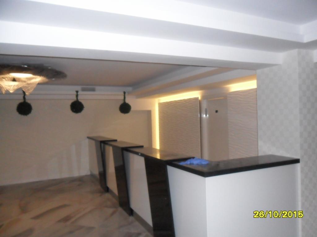 Nowoczesne wykończenie wnętrza: biała lada z czarnym blatem, dekoracyjne kule pod sufitem i podświetlana ściana z fakturą fal. Elegancki design.