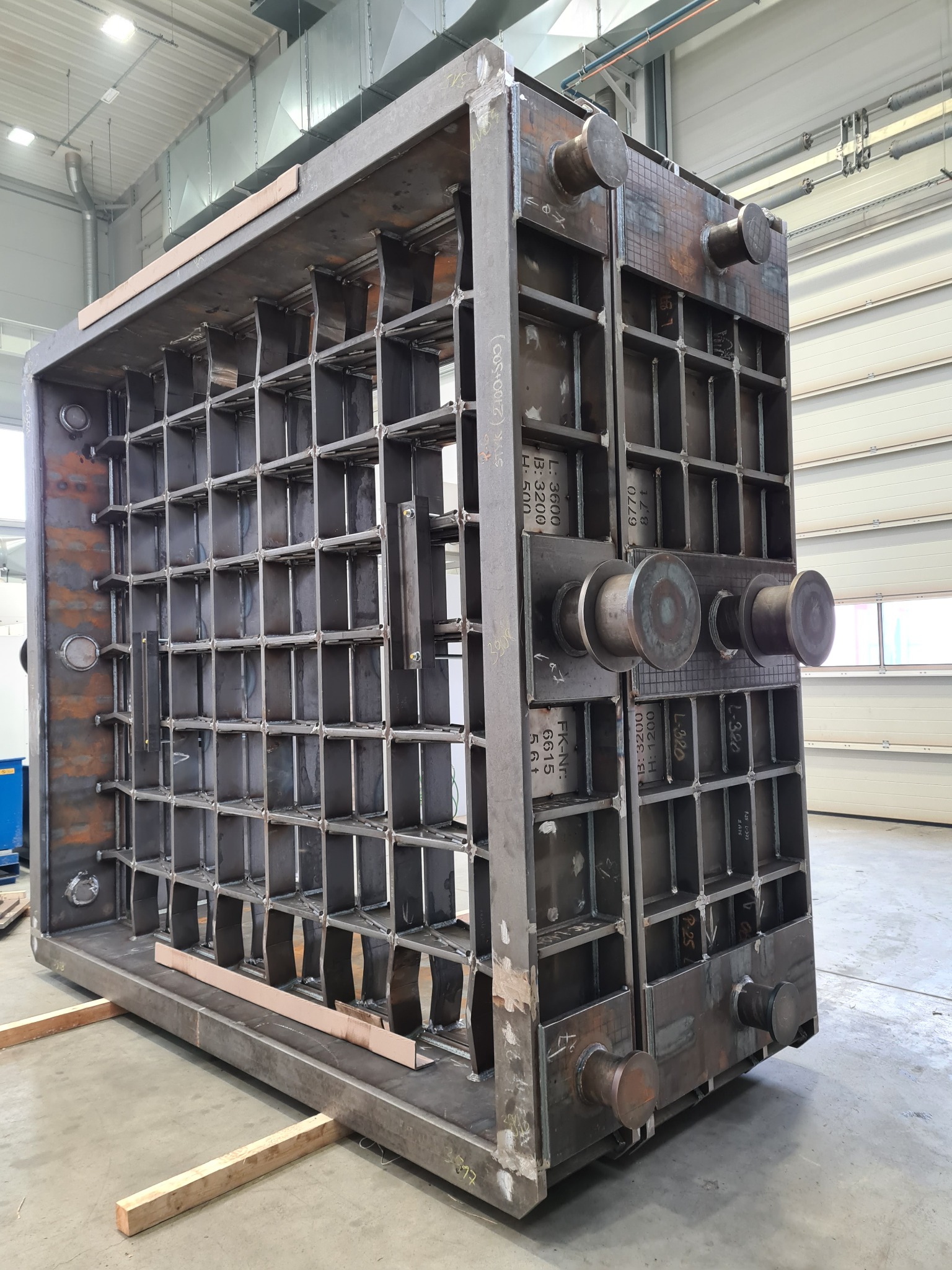 Skomplikowana, spawana konstrukcja stalowa z licznymi wzmocnieniami, widoczna w hali produkcyjnej. Elementy konstrukcji opisane są oznaczeniami technicznymi.