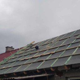 TWÓJ DACH Aleksander Mientki - Dach w trakcie układania papy i łat, widoczne przygotowania do położenia nowego pokrycia, pochmurne niebo w tle.