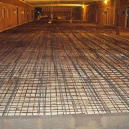 Zbrojenie płyty fundamentowej z widoczną siatką stalową, przygotowane do zalania betonem w surowym wnętrzu budynku.