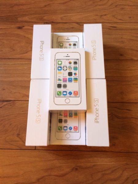 Sześć białych pudełek iPhone 5s ułożonych na drewnianej podłodze, z widocznymi ekranami telefonów na pudełkach.