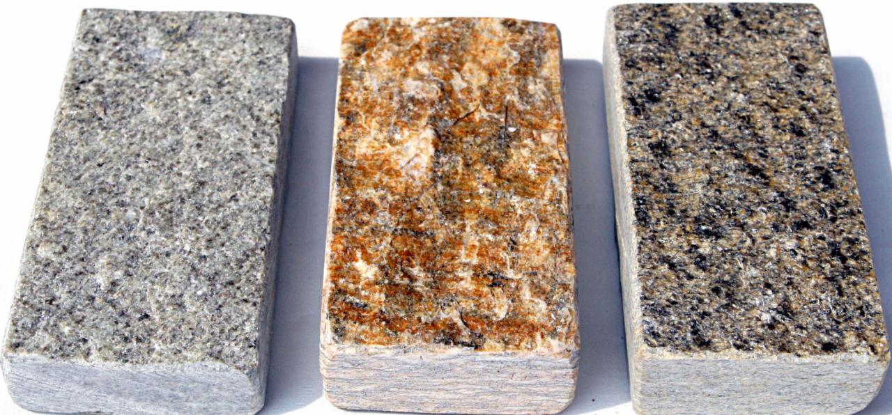 Trzy próbki kamienia o różnej kolorystyce i fakturze, ułożone obok siebie na białym tle, prezentujące szary, brązowo-pomarańczowy i szaro-czarny wariant.