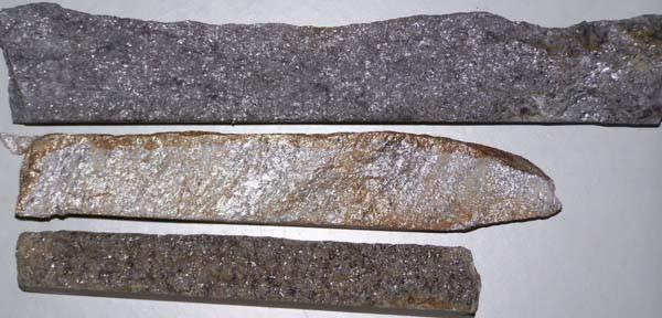 Trzy prostokątne elementy z betonu o różnej fakturze i kolorystyce, ułożone równolegle na jasnym tle.