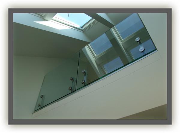 Wewnętrzna balustrada szklana zamocowana punktowo, widok od dołu w kierunku okna dachowego, nowoczesny design.