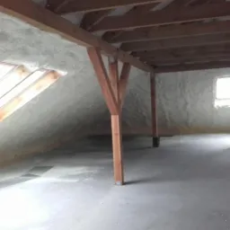 Poddasze z drewnianą konstrukcją i ociepleniem pianką PUR na skosach dachu oraz ścianach. Widoczne okno dachowe i fragment instalacji wentylacyjnej.