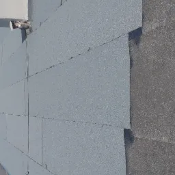 Wykończony płaski dach pokryty szarym materiałem bitumicznym, z widocznymi elementami wentylacyjnymi i fragmentem starej, ciemniejszej powierzchni dachu.