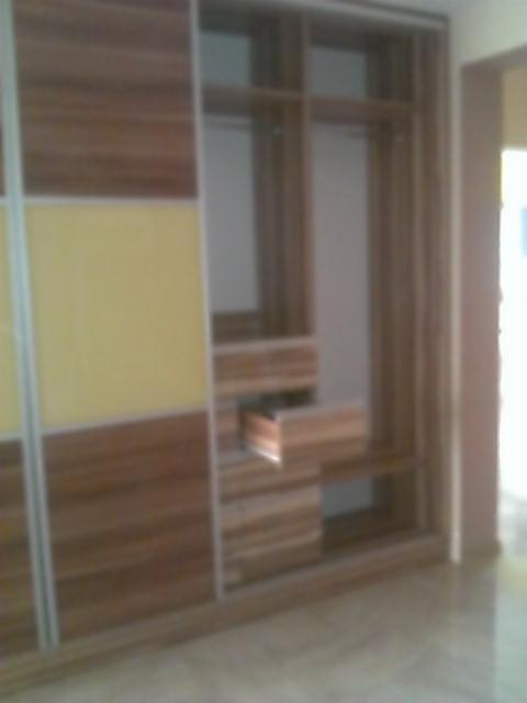 Brązowo-żółta szafa wnękowa z przesuwnymi drzwiami i wysuwaną szufladą, widoczna z perspektywy podłogi.