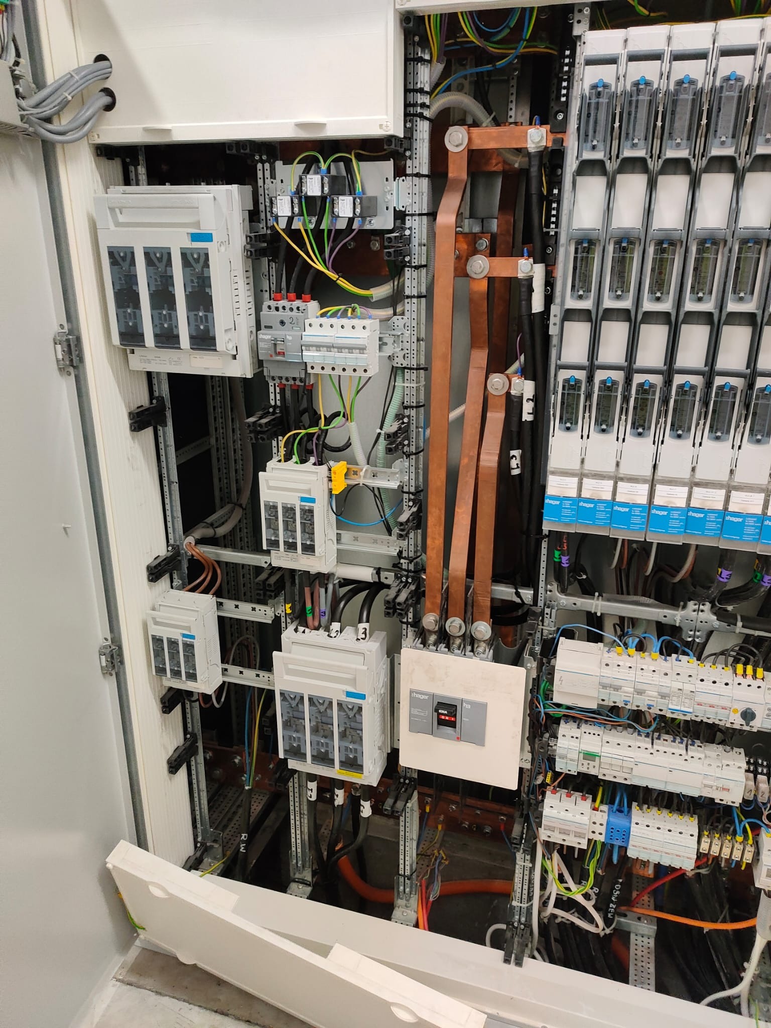 Rozdzielnica elektryczna z widocznymi zabezpieczeniami, przewodami i elementami montażowymi. Widok na wnętrze szafy sterowniczej z zainstalowanymi komponentami.