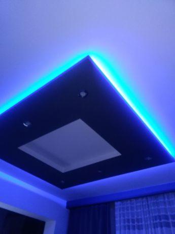 Nowoczesny sufit podwieszany z oświetleniem LED w kolorze niebieskim, z centralnym kwadratowym wgłębieniem i punktowymi lampami.